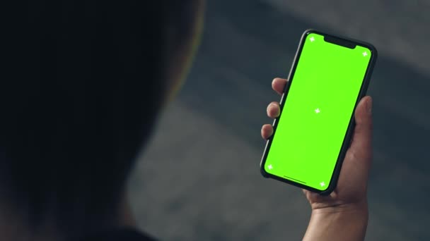 家庭で緑の画面のスマートフォンを使ってフィットネス女性のバックビュー。スマートフォンでワークアウトの準備をする女性フィットネストレーニング中に携帯電話でタップを行う女性 — ストック動画