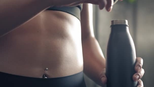 Backlit close up de abs mulher fitness ao levantar garrafa esporte para beber. Atleta mulher abs músculos detalhe. Abs construção muscular realização . — Vídeo de Stock