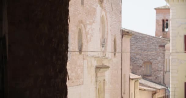 Widok średniowiecznych budynków i murów w zabytkowym mieście Spello, Włochy. Widok wąskiej ulicy z kościołem w starym włoskim mieście. Strzał ręczny — Wideo stockowe