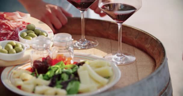 Detalhe de homem e mulher mãos tomando copos de vinho. Detalhe da mesa com aperitivo de queijo de comida de dedo no pôr do sol quente. Mão pegando um copo de vinho. Um tiro de perto. Amigos viagem italiana.4k câmera lenta — Vídeo de Stock