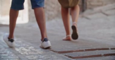 Küçük caddelerde yürüyen dört mutlu turist. Bir adım uzaktayken bacakların düşük görünümü. Eski şehirde yürüyen çok ırklı bir grup insan. İtalya 'da tatil.