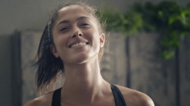 Gülümseyen fitness kadını evde portre geriyor. Evde kişisel antrenör. Evde antrenman yaparken gülümseyen bir kadın. Kadın antrenman sırasında dinleniyor. El kamerası atışı.