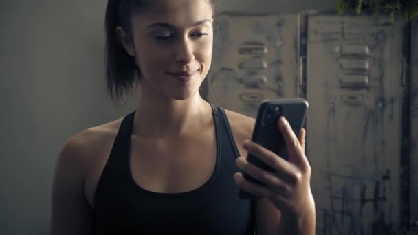 Kobieta korzystająca ze smartfona z osobistą aplikacją treningową w domu. Kobieta przygotowująca się do treningu za pomocą aplikacji fitness. Zamknij orbitę zdjęcia.Kobieta korzystająca z telefonu komórkowego podczas odpoczynku podczas treningu fitness — Wideo stockowe