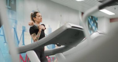 Spor salonunda koşu bandında gerinen genç bir kadın. Spor salonunda Bayan Kadın Antrenmanı. Kardiyo egzersizi yapan kadın.