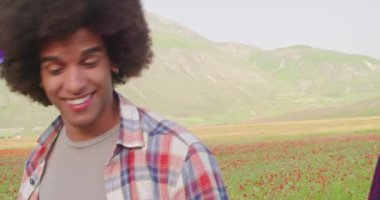 Kırmızı bir çiçek tarlasının yanında yürüyen iki kişi. Gülümseyen kadın dışarıda yürürken mutlu omuzlara atlıyor. Mutlu kadın, erkeğin üzerine atlıyor şakalaşıyor ve doğa yürüyüşünden zevk alıyor. 