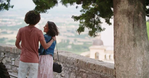 Visão traseira do abraço casal romântico olhando para o ponto de vista na cidade rural de Assisi.Portrait tiro médio.Amigos viagem italiana na Úmbria — Fotografia de Stock