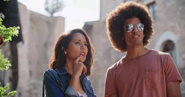 Uomo e donna puntano il dito durante la ricerca di servizi o punti di riferimento in città rurale.slow motion. Due persone sorridenti mentre puntano il dito nella città rurale italiana.Ritratto medio scatto Foto Stock