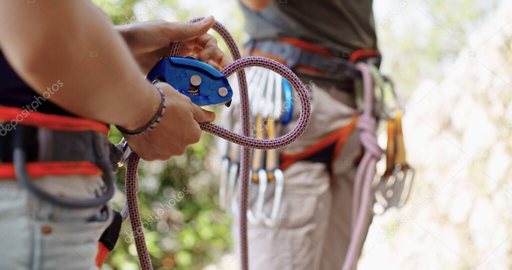 Climber man preparing for climbing up the rocky wall rift by checking rope. Climbing extreme active sport activity. Active people, outdoor activities.Hands and rope detail.