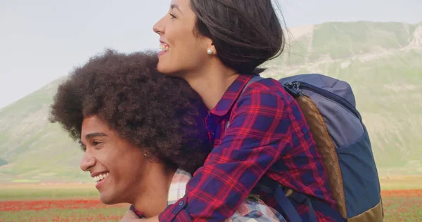 Hombre camina con la mujer sobre sus hombros. Vista lateral de cerca. Mujer en hombreras mientras camina al aire libre.Detalle de vista lateral. Hombre feliz caminando con mujer sonriente en hombros. — Foto de Stock