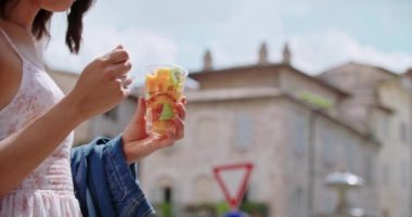 Şehirde ya da eski kasabada meyve salatası yiyen bir kadın. Turist güneşli bir günde meyve salatası yerken mola verir. Çatalla meyve salatası toplayan bir kadın.
