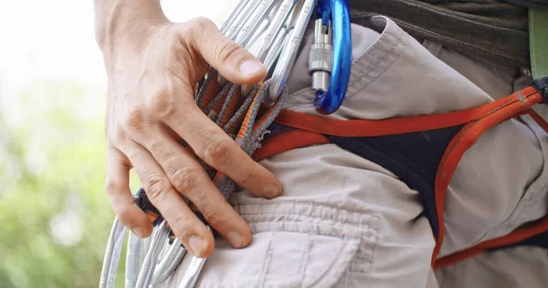 Uomo arrampicatore che si prepara a scalare la spaccatura della parete rocciosa ottenendo moschettoni. Arrampicata estrema attività sportiva attiva. Persone attive, attività all'aperto. Dettaglio. Fotografia Stock