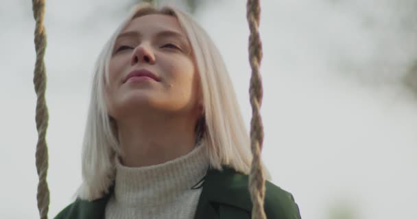 Des souvenirs positifs refont surface pour une jeune et belle femme tout en balançant et en tenant un livre, en automne. Mouvement lent — Video