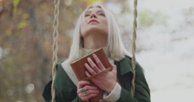 Sonbaharda sallanan ve elinde kitap tutan genç ve güzel bir kadın için olumlu anılar tekrar su yüzüne çıkar. Yavaş çekim