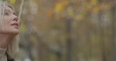 Genç ve güzel bir kadın gökyüzüne bakıyor, bir sonbahar gününde sallanıyor ve gülümsüyor. Yavaş çekim