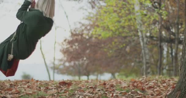 Slow motion of young woman swinging and playing like a chid. Young woman smiling in a cold autumn day. — Stock Video