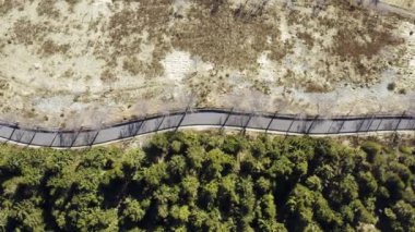 Güneşli bir günde, kış mevsiminde ormanın yanındaki yolda. Kış yolu hava manzarası 