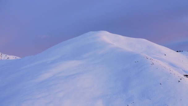 Vista aérea de una cresta de montaña de invierno antes del amanecer o después del atardecer. La nieve cubrió la cima de la montaña durante el atardecer. Nieve inmaculada de color. cámara lenta — Vídeo de stock