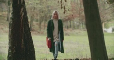 Sonbaharda şehir hayatından kaçmak için ormanda tek başına yürüyen genç bir kadın. Ağır çekim. Ormana giren kadın
