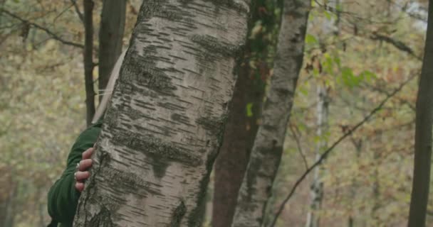 Giovane donna bionda timida cammina sulle foglie intorno a un albero in autunno. Rallentatore — Video Stock