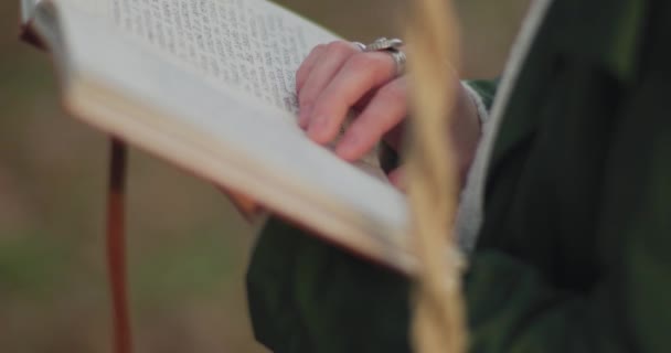 Detail rukou mladé ženy čtení knihy uniknout do každodenní rutiny v podzimním dni. zpomalený pohyb — Stock video