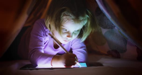 Bambino ragazza caucasica bionda colorazione digitale con tablet app sotto coperta letto di notte. Tecnologia moderna bambino uso infantile a casa. 4k video — Video Stock