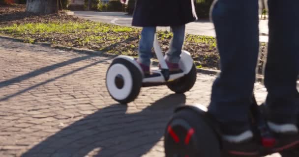 Detal segway z córka i tata riding.Modern przyszłej technologii transportowej.Active Family.Park chodnik miejski na świeżym powietrzu.Ciepłe zachody słońca zimne podświetlenie pogody.4k powolny ruch 60p wideo — Wideo stockowe