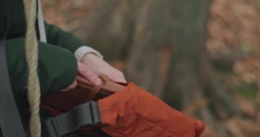 Genç bir kadın çantasından bir günlük kitabı çıkarıyor ve sonbaharda bir salıncakta kollarında sıkıca tutuyor. yavaş çekim