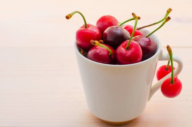 Tahta arka planda seramik kasede taze kirazlar.