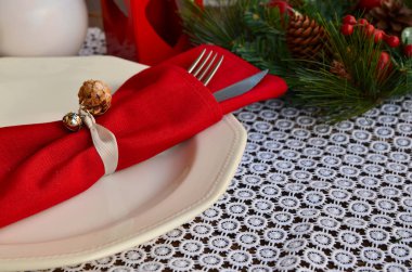 Noel sofrası ayarları kırmızı tonda. Geleneksel köknar ağacı sürüsü, kırsal arka planda çatal bıçaklı kırmızı peçete. Şenlikli yemek için dekorasyon Kopyalama alanı 