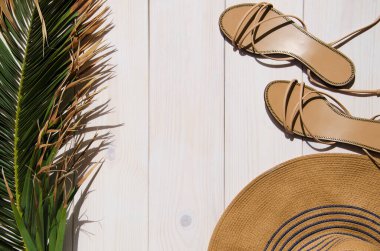 Tropik palmiye yaprağı, güneş şapkası ve sandaletler beyaz ahşap arka planda fotokopi alanı ile. Tatil ya da yaz tatili kavramı.