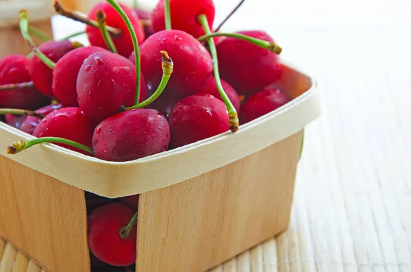 Organic cherries  with water drops in wood basket