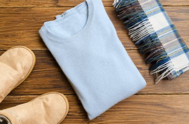 Düz yatıyordu. Mavi kaşmir kazak, ugg botlar ve ahşap arka planda yün kare atkı. Kış zamanları ve Noel için konsept. Boşluğu kopyala.