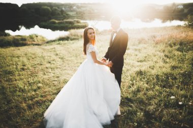 Güzel romantik bir çift yeni evliler gün batımında parkta sarılıyorlar.