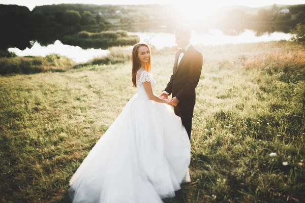 Güzel romantik bir çift yeni evliler gün batımında parkta sarılıyorlar. — Stok fotoğraf