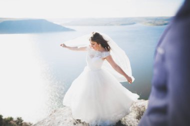 Şık, şık, mutlu bir düğün çifti, gelin, deniz ve gökyüzünün arka planında muhteşem bir damat.