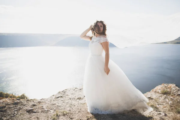 Hezká dáma, nevěsta pózuje ve svatebních šatech u moře při západu slunce — Stock fotografie