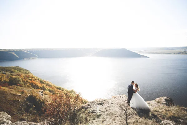 Hochzeitspaar küsst und umarmt sich auf Felsen nahe blauem Meer — Stockfoto