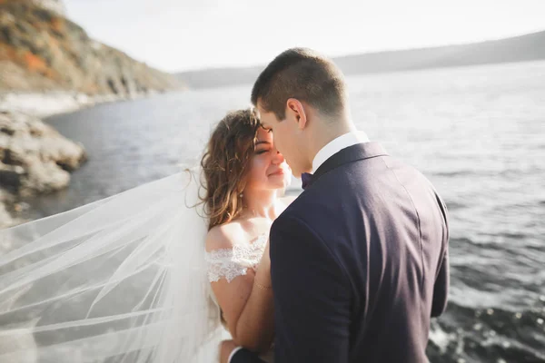 En lykkelig og romantisk scene der et ungt ektepar poserer på en vakker strand. – stockfoto