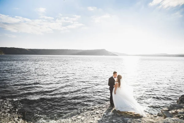 Elegante pareja de boda feliz elegante, novia, magnífico novio en el fondo del mar y el cielo —  Fotos de Stock