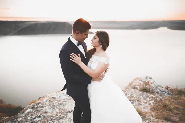 Matrimonio coppia baci e abbracci su rocce vicino al mare blu — Foto Stock