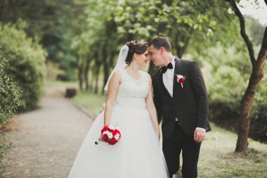 Yeni evli çift el ele tutuşurken parkta koşup zıplıyorlar.