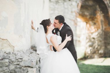 Güzel, romantik bir düğün. Yeni evliler. Eski kalenin yakınlarında sarılıyorlar.