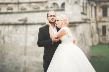 Güzel, romantik bir düğün. Yeni evliler. Eski kalenin yakınlarında sarılıyorlar.