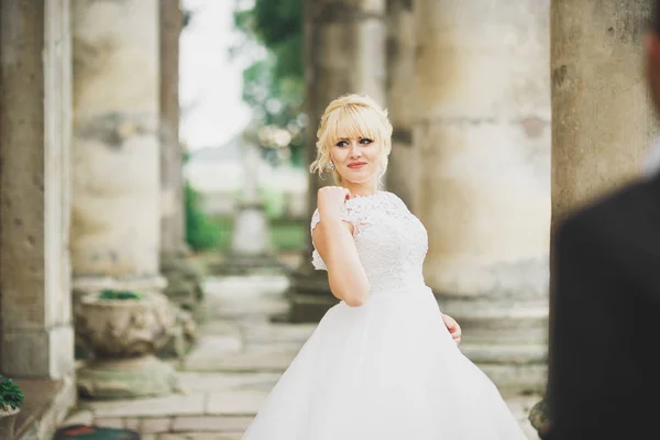 Hermosa novia elegante con vestido de novia perfecto y posando ramo cerca del viejo castillo —  Fotos de Stock