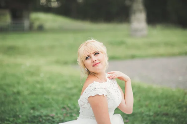 Hermosa novia joven de lujo en vestido de novia posando en el parque — Foto de Stock