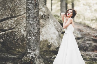 Güzel gelin orman kayalar ile poz bir buket ile. Açık havada