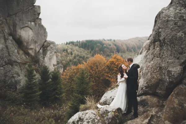 Boda pareja enamorada besándose y abrazándose cerca de rocas en hermoso paisaje —  Fotos de Stock