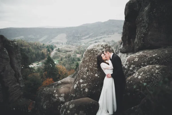 Svatební pár v lásce líbání a objímání v blízkosti skal na krásné krajině — Stock fotografie