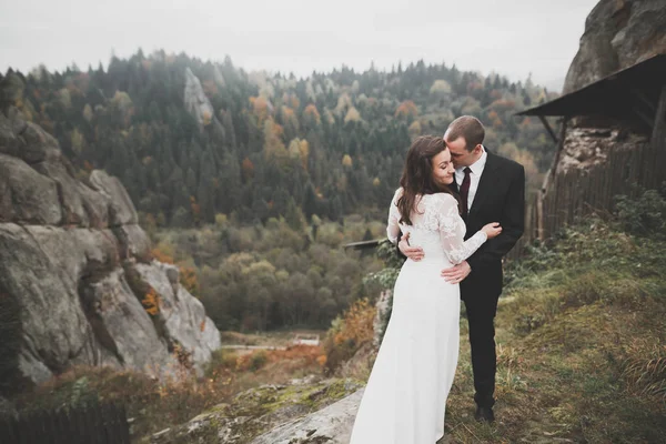 Bruiloft koppel in liefde kussen en knuffelen in de buurt van rotsen op prachtig landschap — Stockfoto