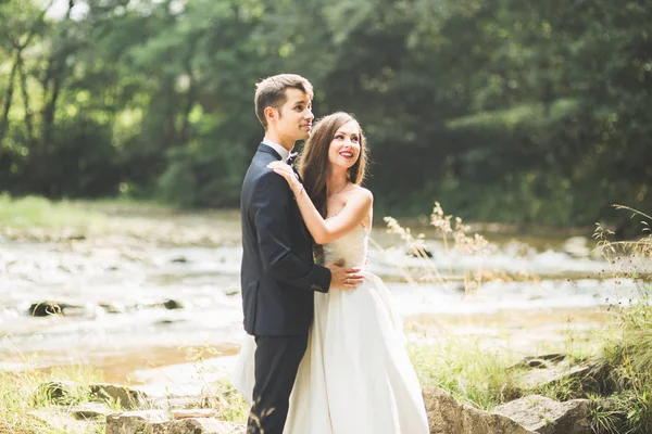 Свадебная пара, обнимание жениха и невесты, на открытом воздухе возле реки — стоковое фото